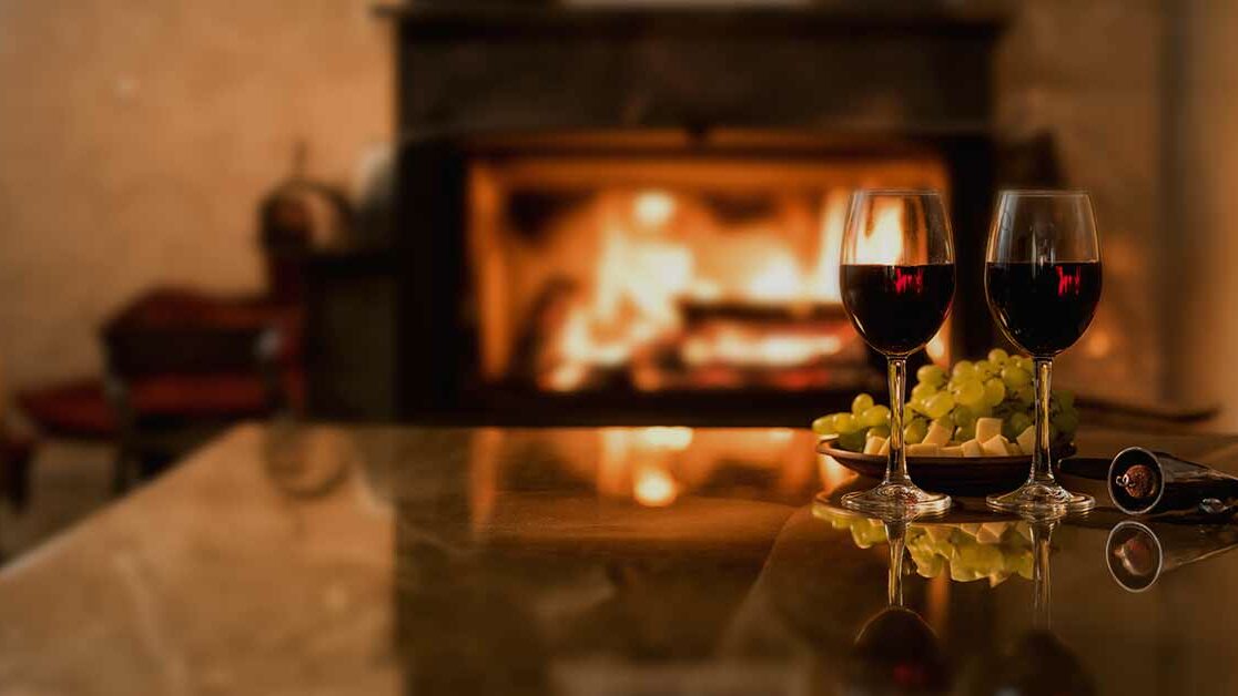 two,red,wine,wineglasses,over,fireplace,background.