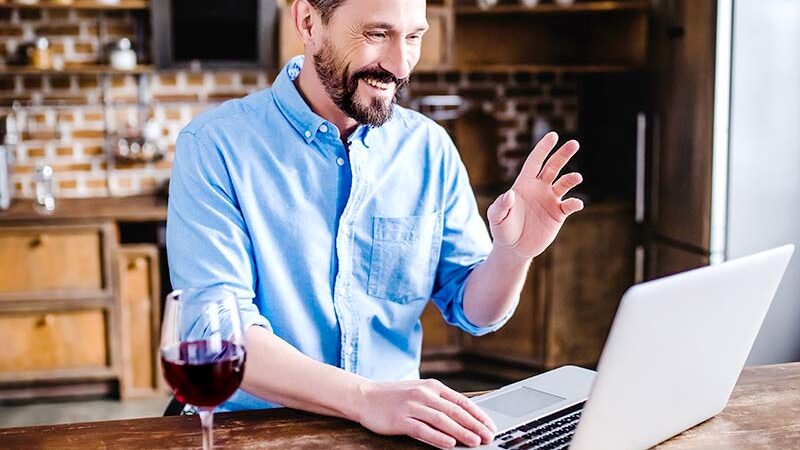 man having wine using laptop