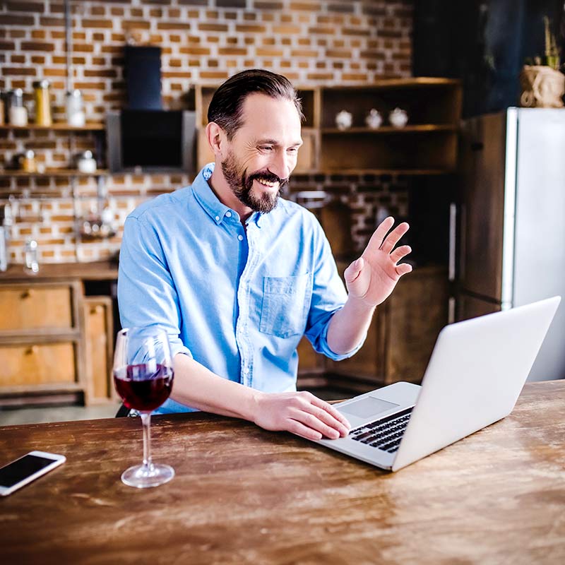man having wine using laptop